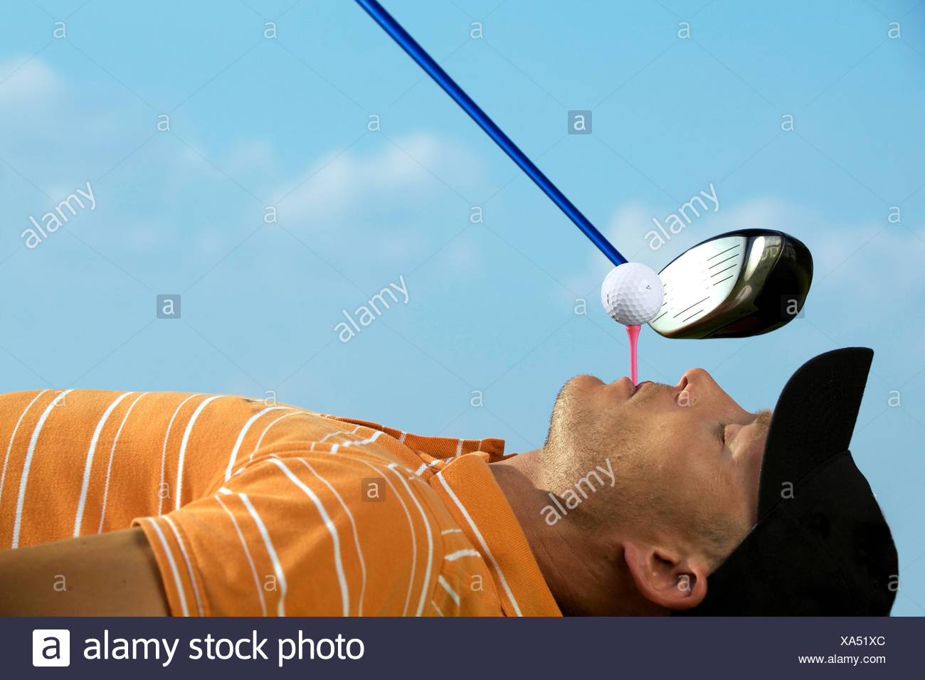 Man balancing golf ball on tee in his mouth Stock Photo