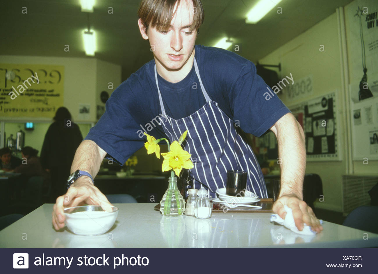Student Working In College Canteen Clearing Tables To