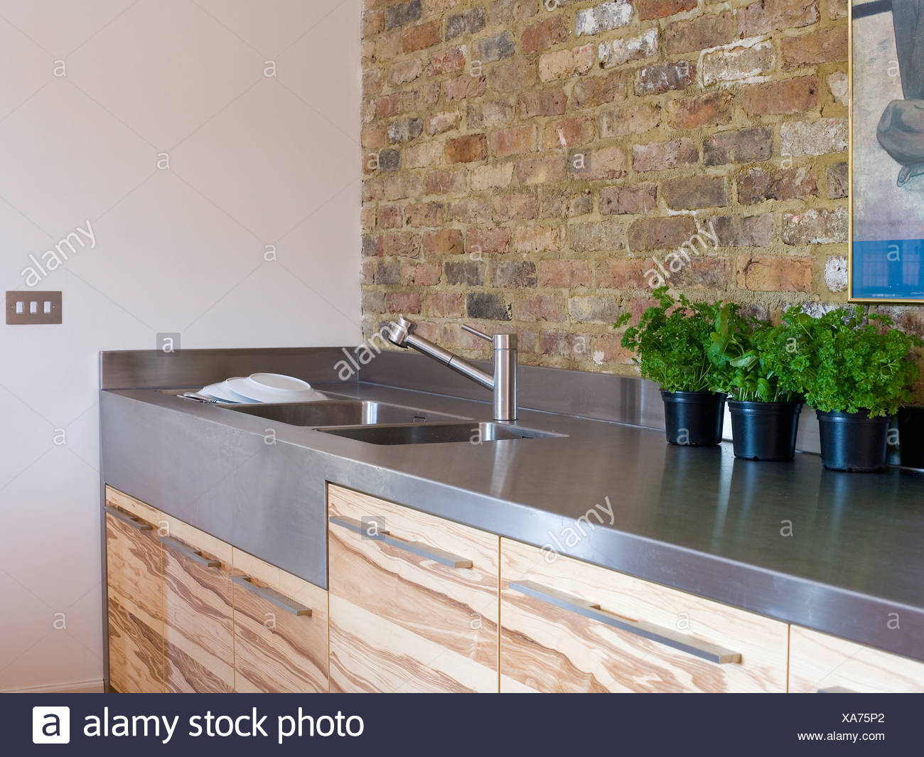 Exposed Brick Wall Above Stainless Steel Worktop On Wood Veneer