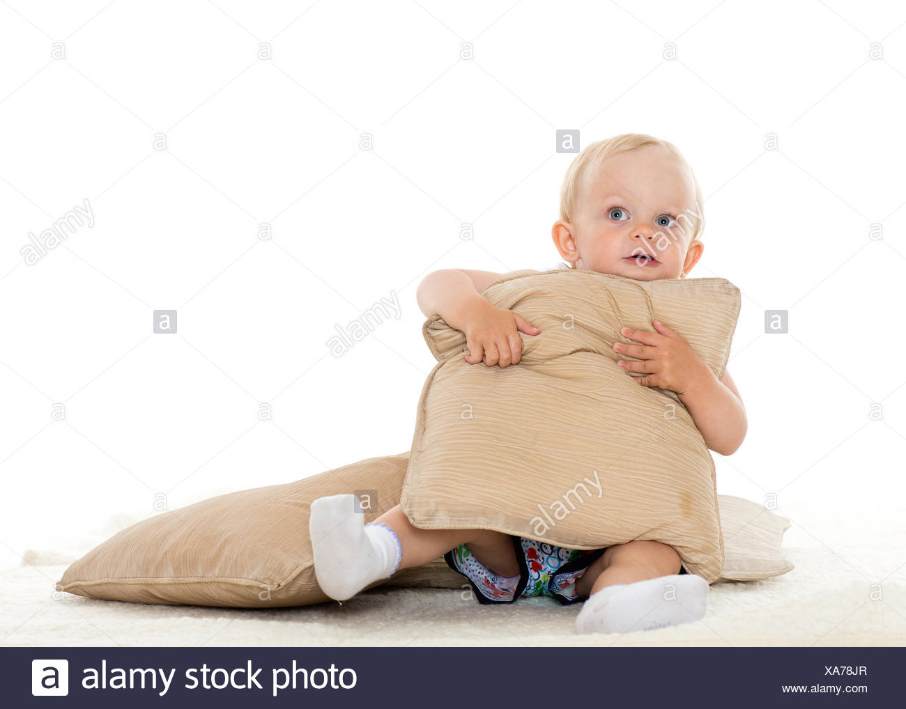Sweet Small Baby Is Playing With Pillows On A White Background