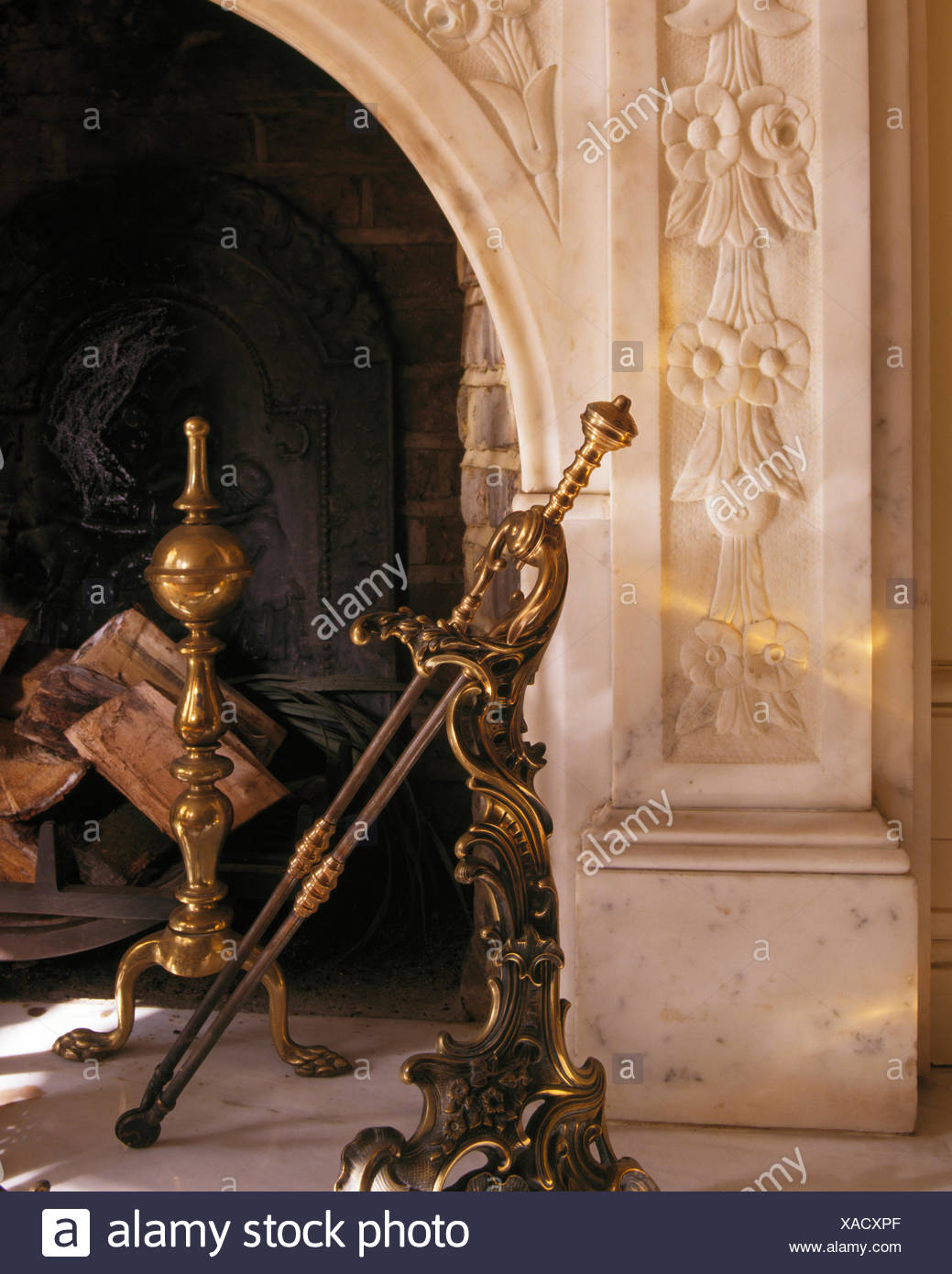 Close Up Of Brass Fire Tongs And Fire Dogs In Marble Fireplace