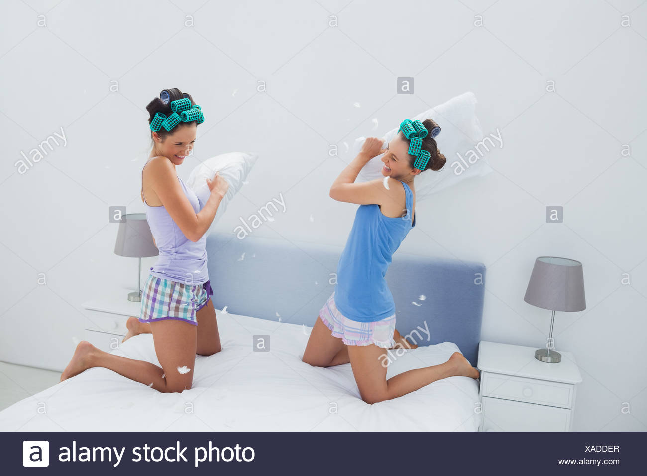 Girls In Hair Rollers Having Pillow Fight Stock Photo 281808431