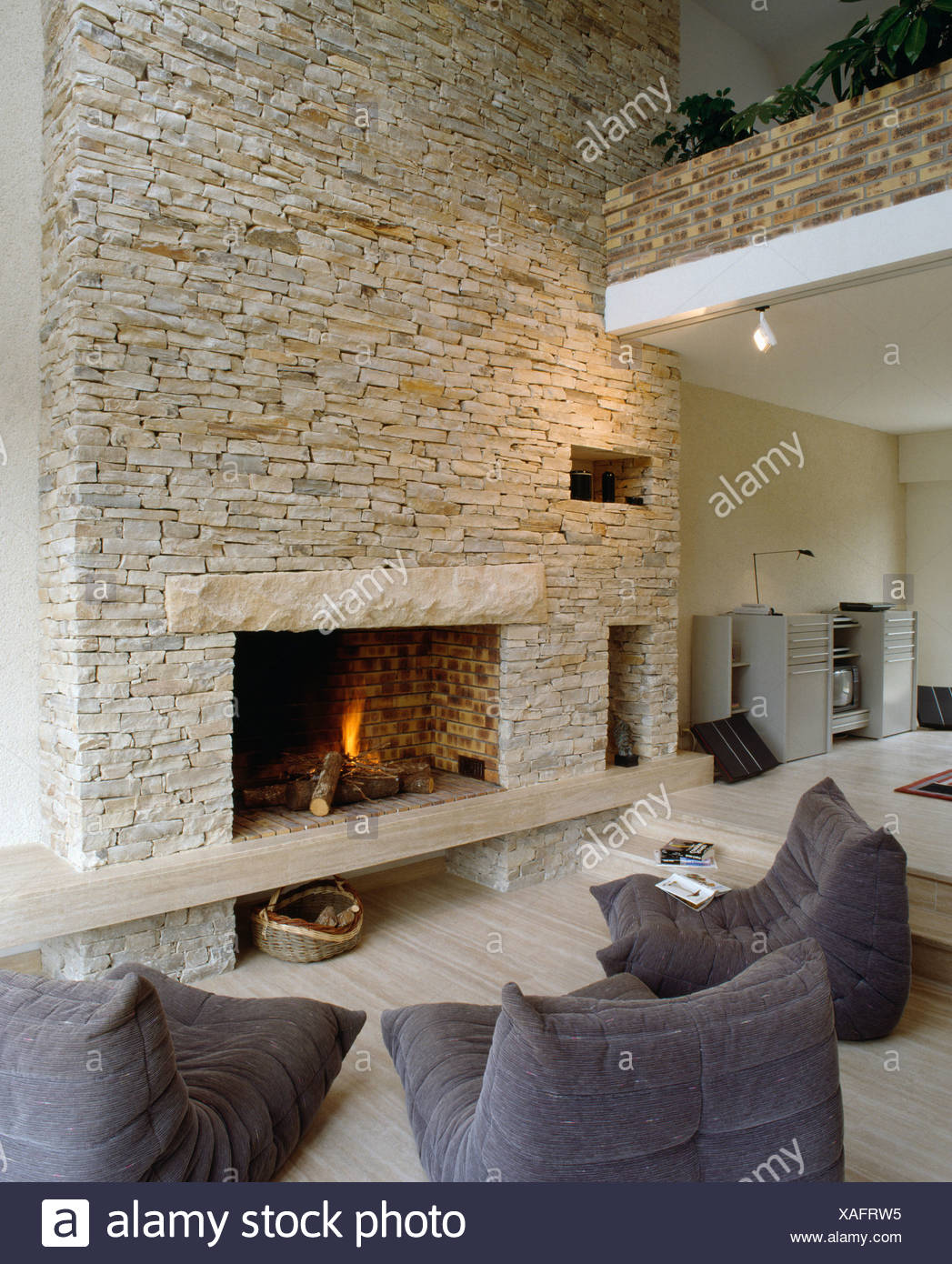 Lit Fire In Fireplace In Stone Wall Of Barn Conversion With