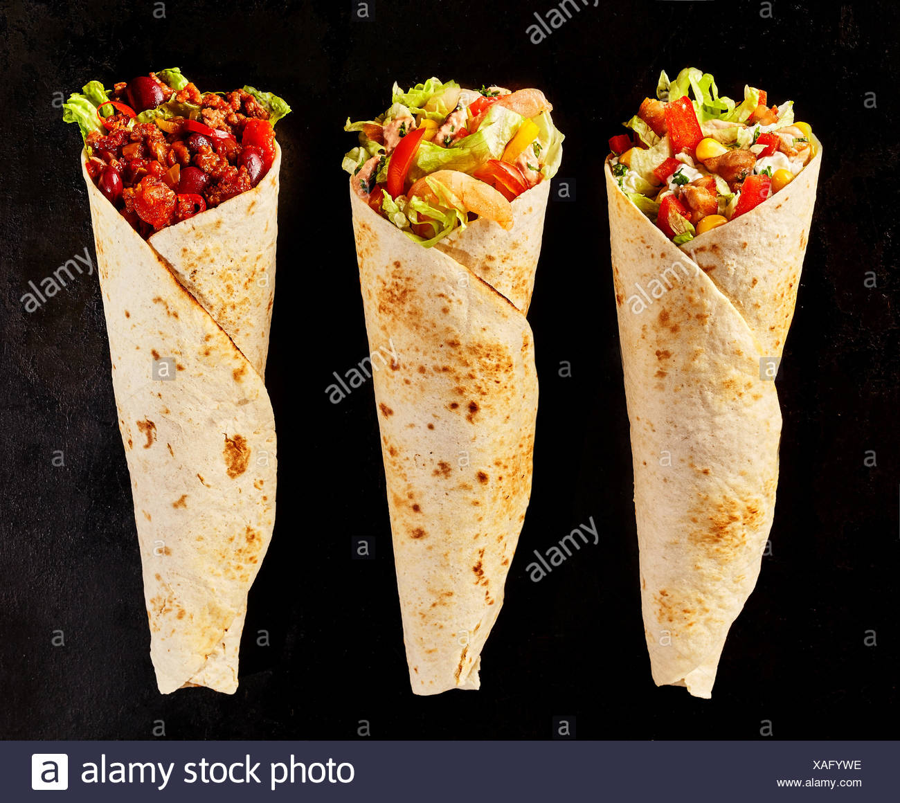 High Angle Still Life of Trio of Tex Mex Fajita Wraps on Black ...