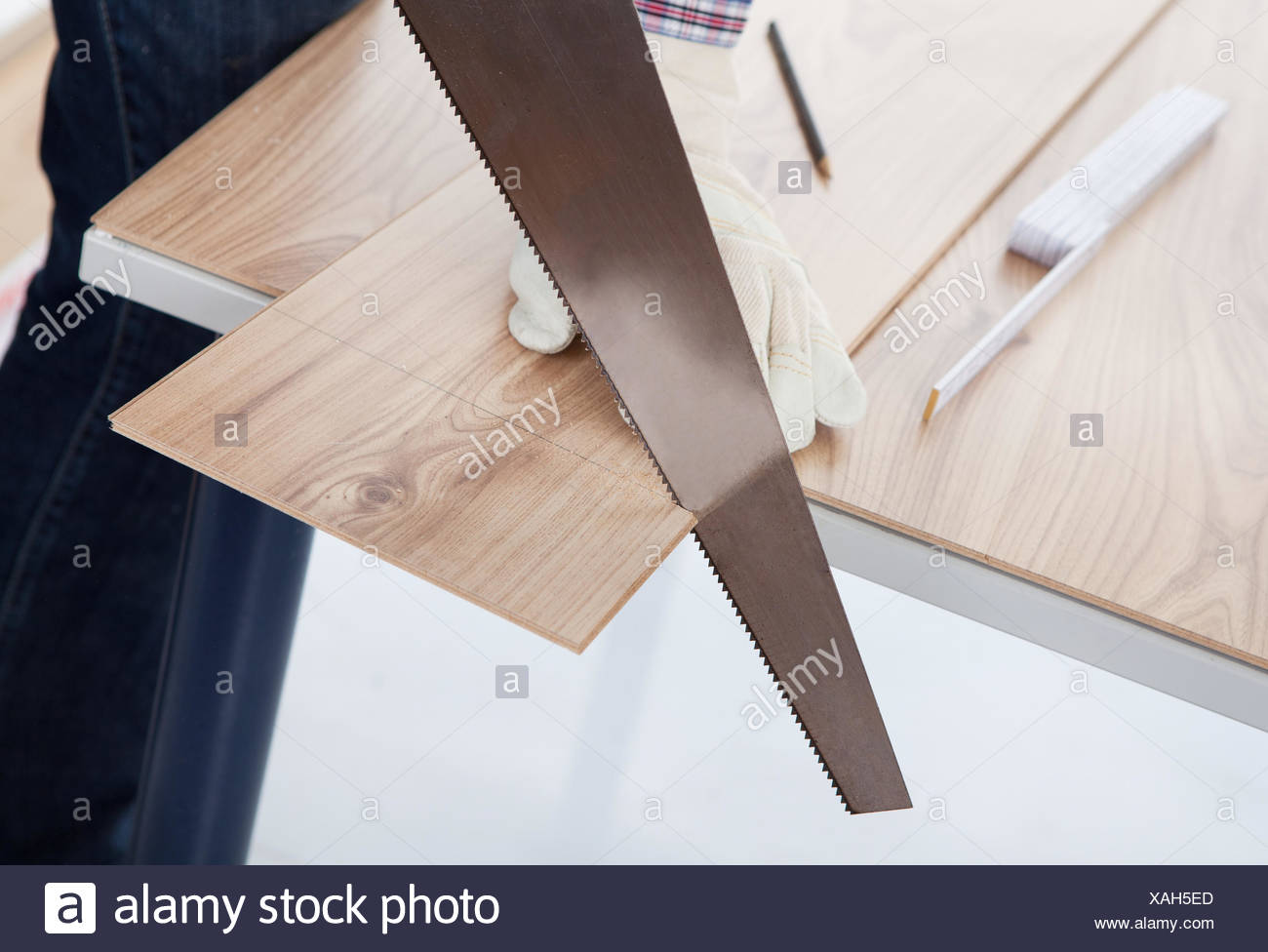 Worker Cutting Piece Of Laminate Using Hand Saw Stock Photo