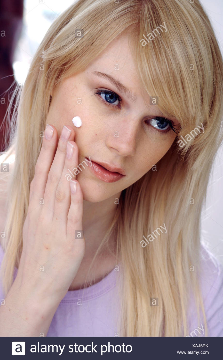 Female With Long Straight Blonde Hair Applying Face Cream