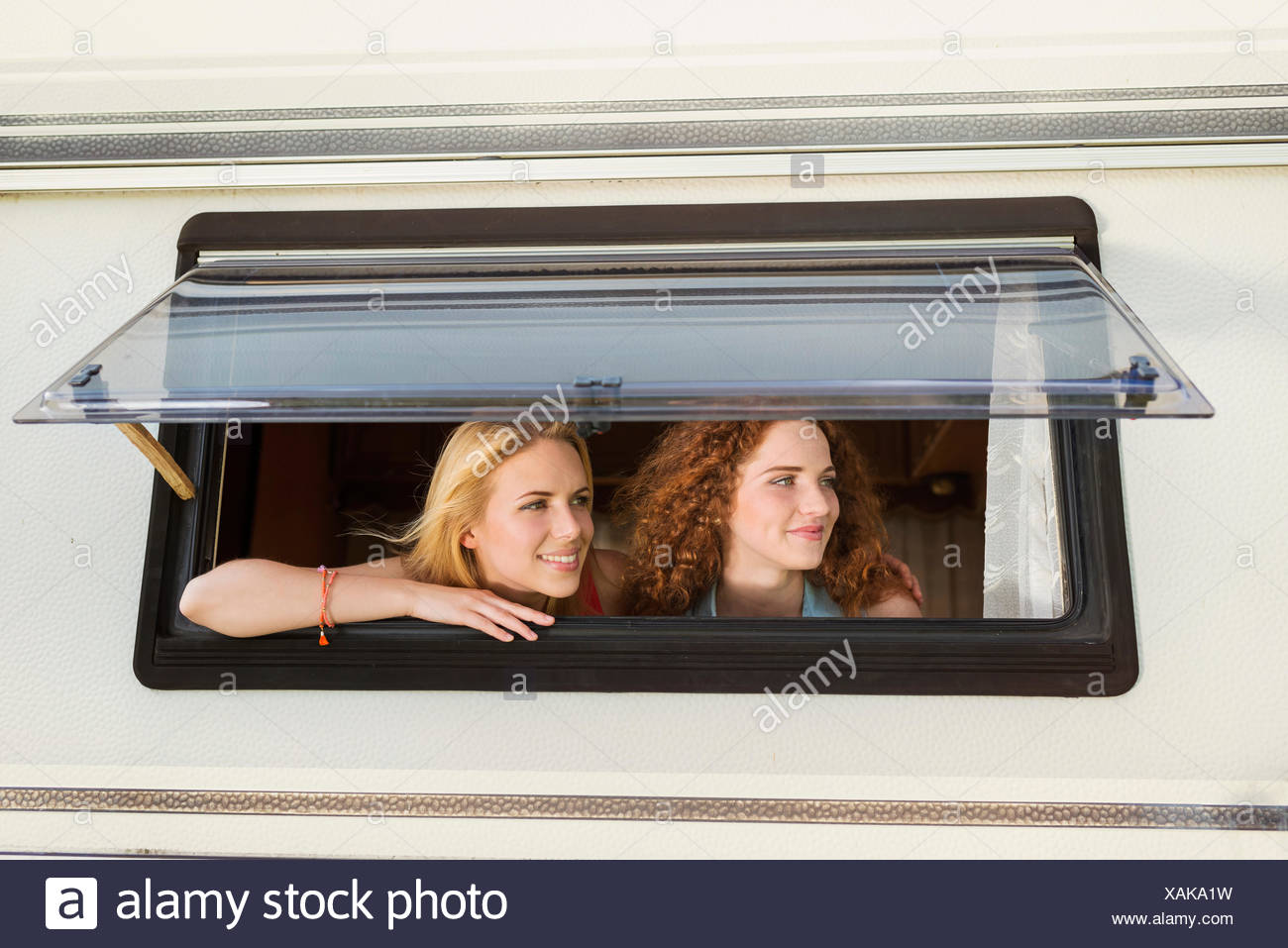Two Female Friends Looking Through Window Of Caravan Watching