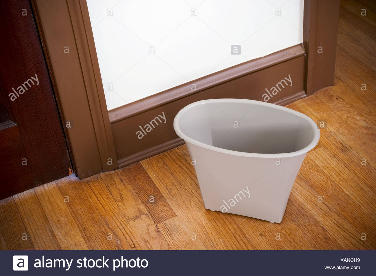Small Wastebasket On A Hardwood Bedroom Floor Stock Photo