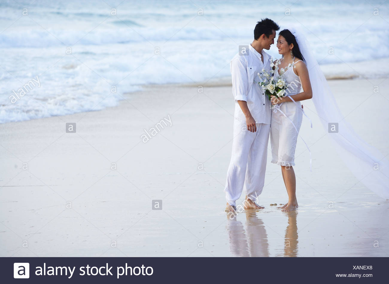 Bride And Groom On Beach Standing Face To Face Stock Photo