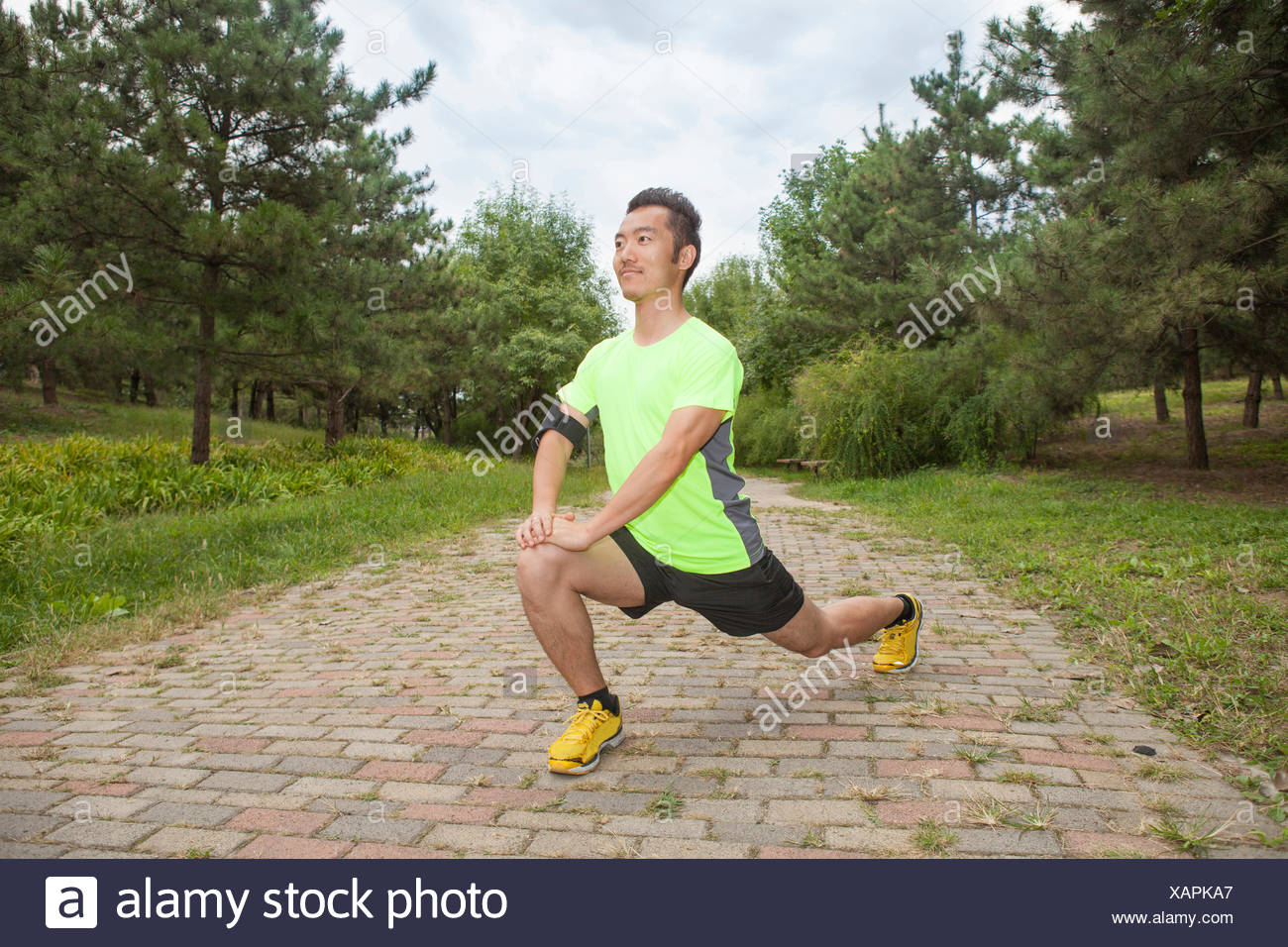 Young male runner stretching legs in park Stock Photo