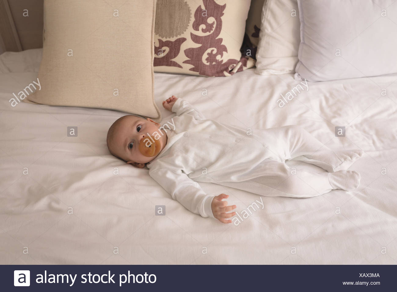 Cute little baby with pacifier in mouth sleeping on bed Stock Photo
