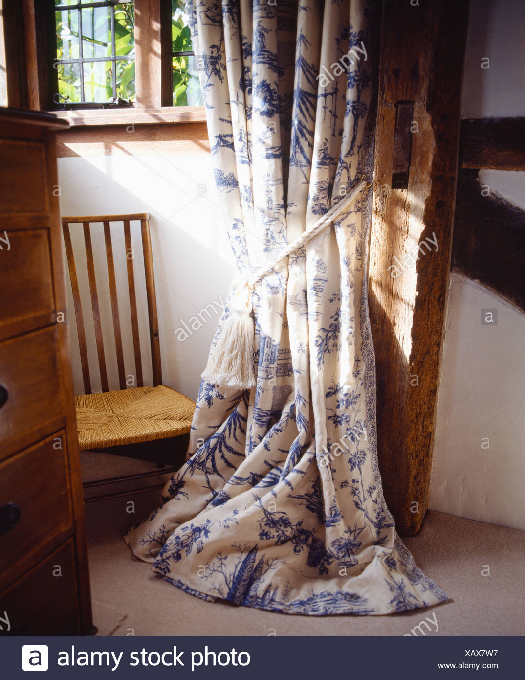 Close Up Of Blue White Floral Curtains On Window Above Rush Seated