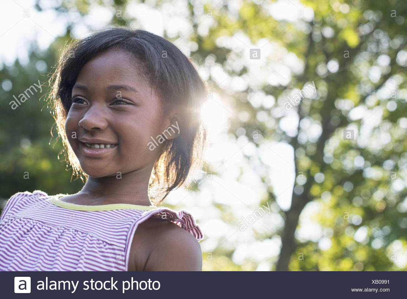 A Young Girl With Short Hair In A Striped Sundress Smiling Stock