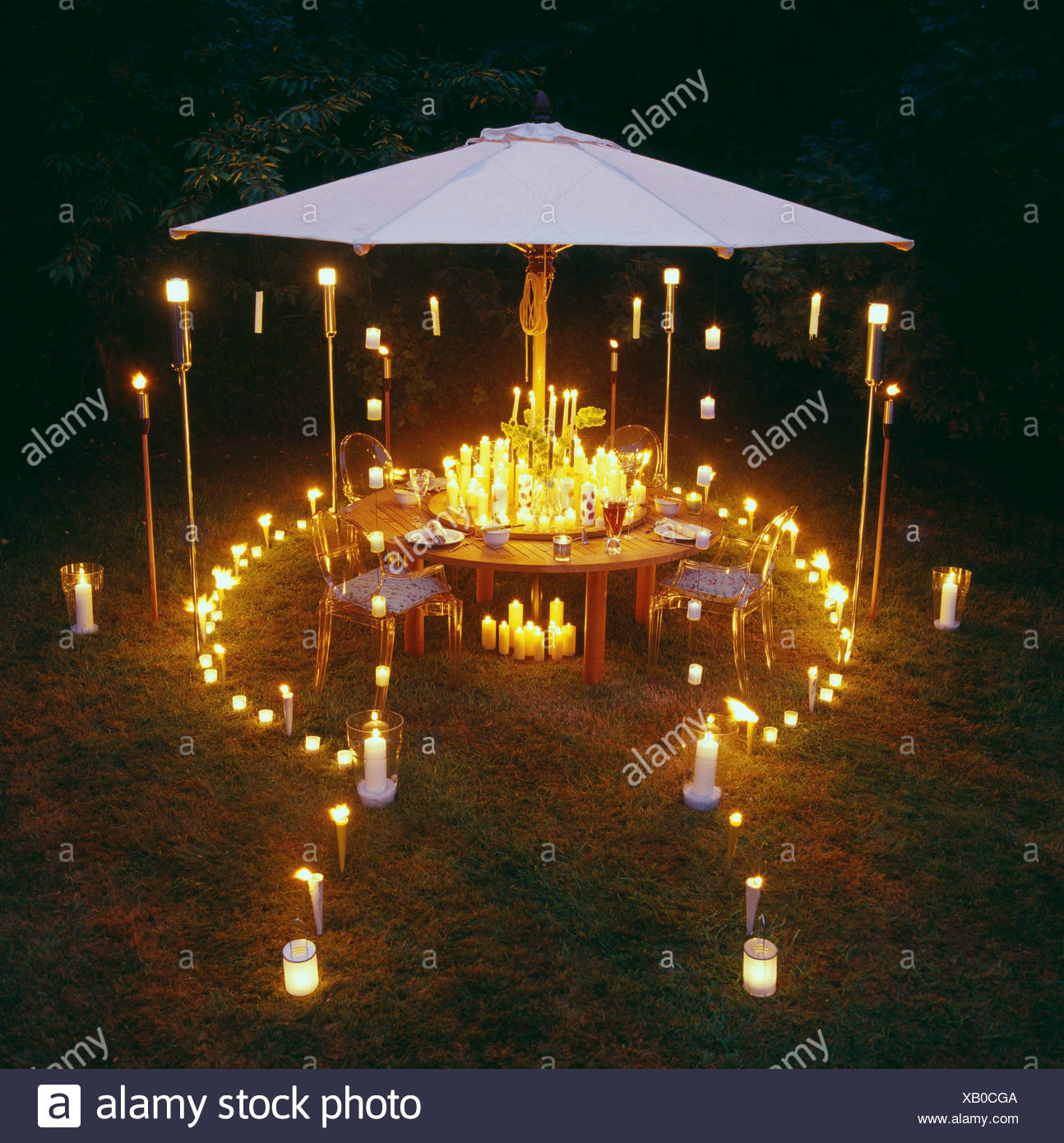 Candlelight Garden Party Large Round Wood Dining Table Four Chairs Centrepiece Of Variety Of Burning Candles Candles In Stock Photo Alamy