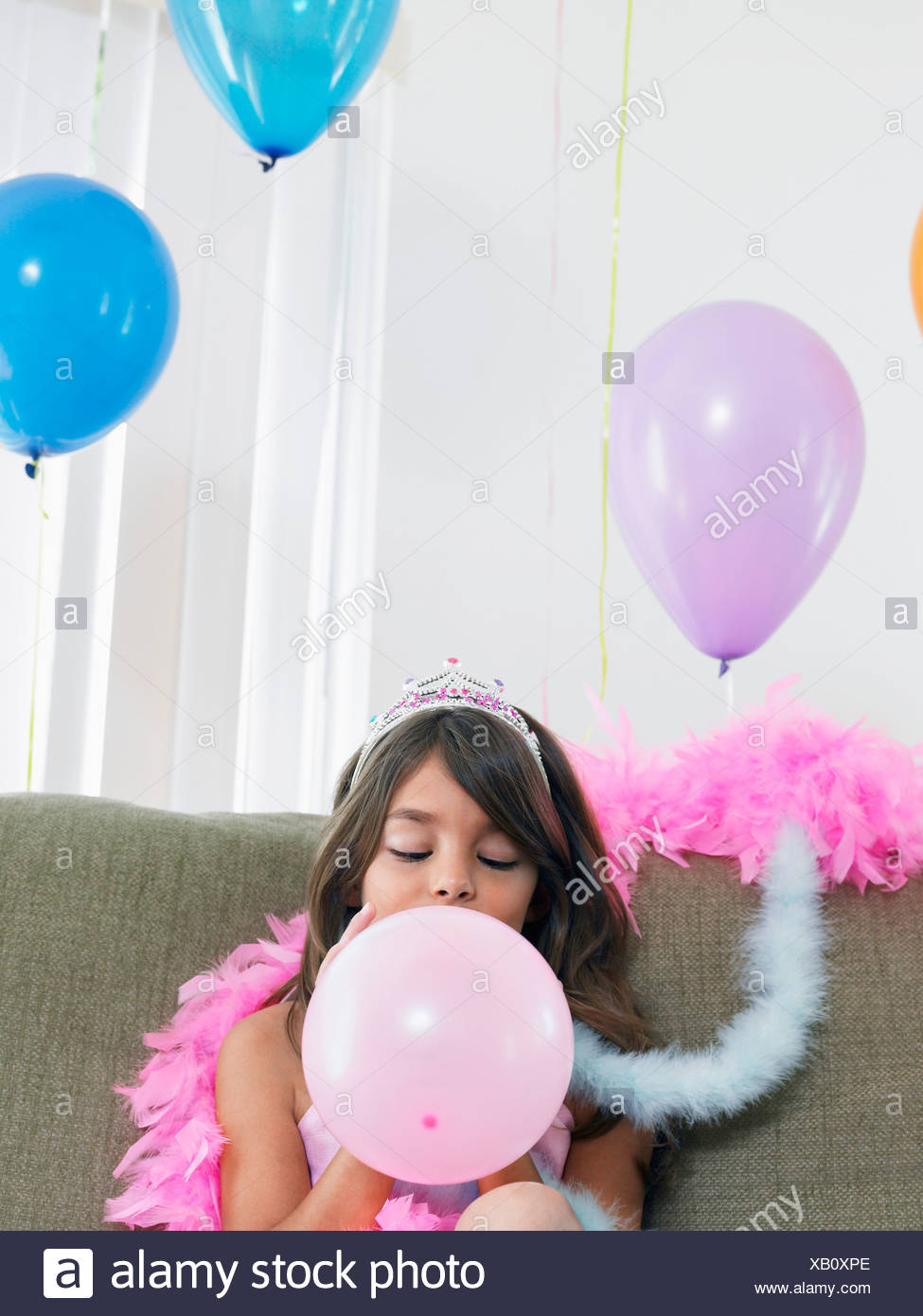 Young Girl 7 9 Sitting On Sofa Blowing Up Balloon Stock Young Girl 7 9 Sitting On Sofa Blowing Up Balloon Stock