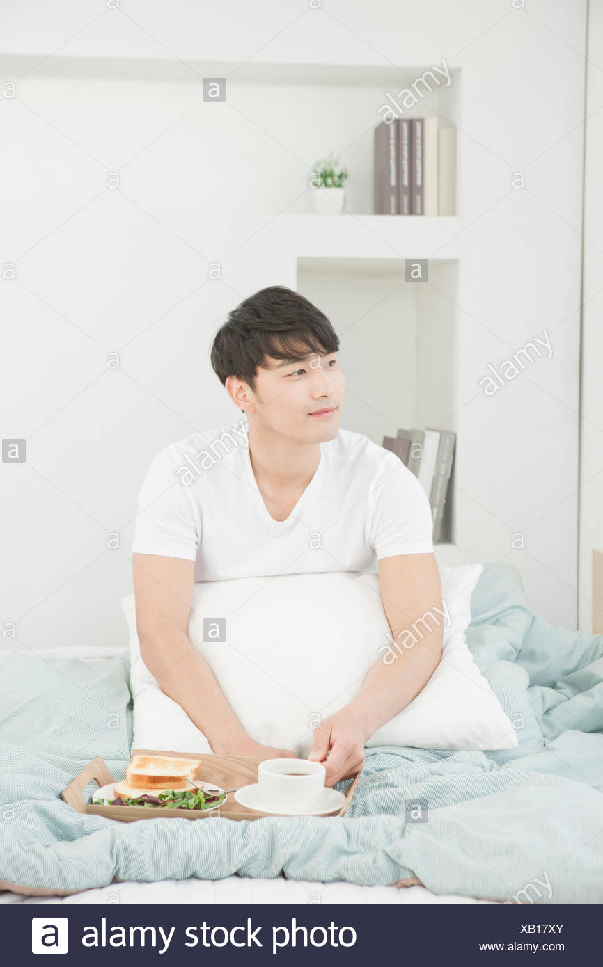Man Placing A Pillow Under His Arm And Sitting In Bed With The