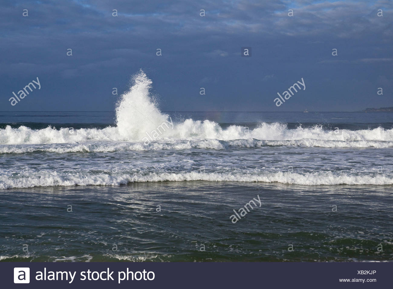 Two Waves Combine To Create One A Plume Of Spray And Mini Rainbow