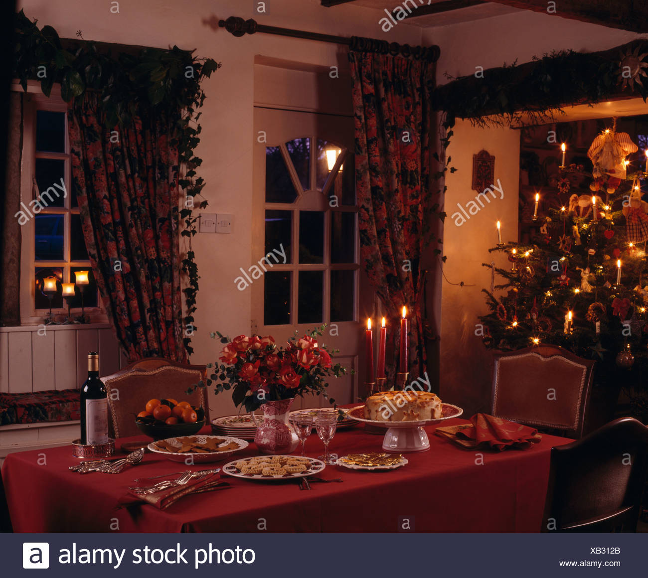 Red Cloth On Table Set For Christmas Tea With Lighted Candles In