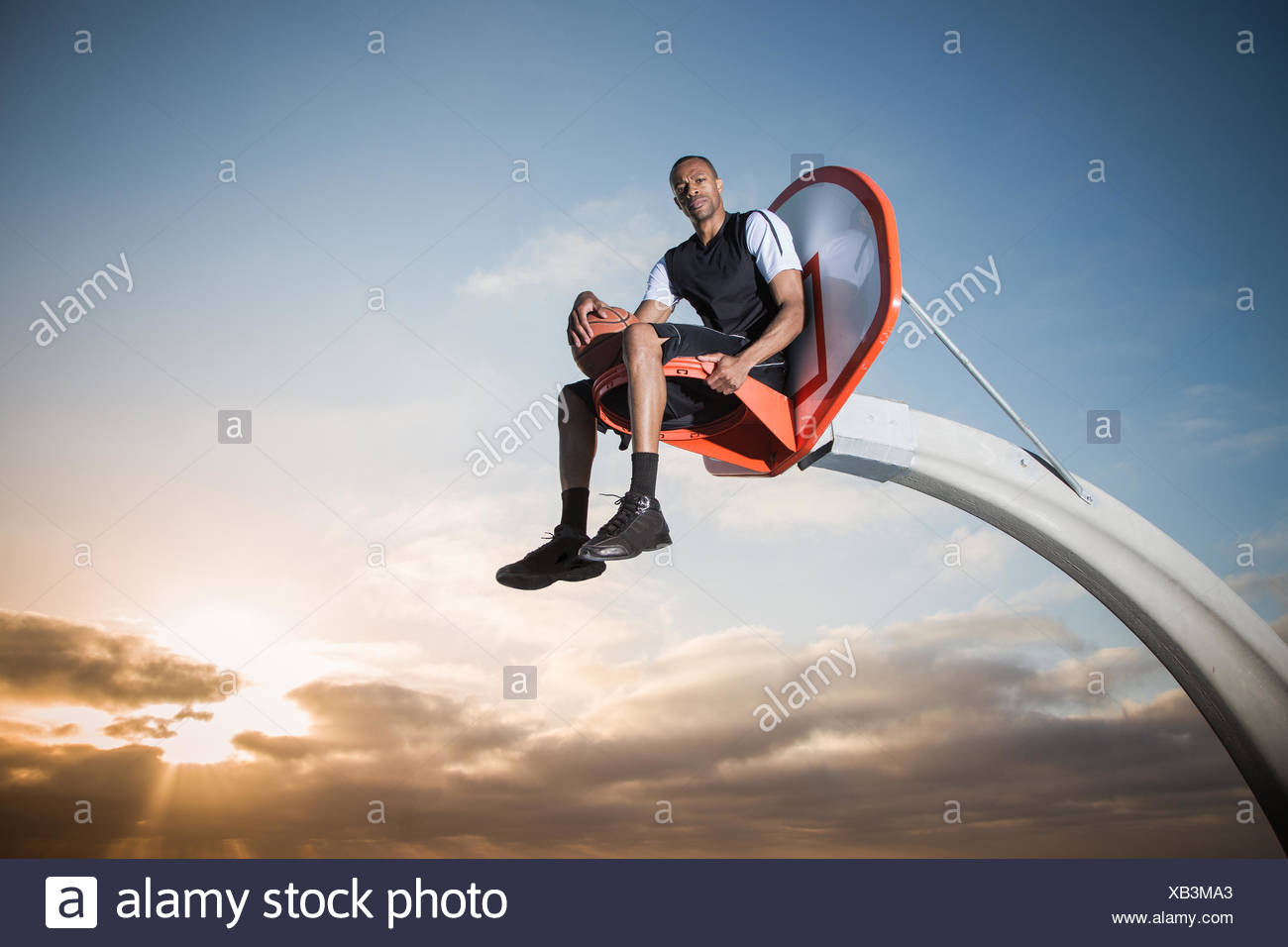 Portrait of a young man sitting in a basketball hoop in a park, Los Angeles, California, USA Stock Photo