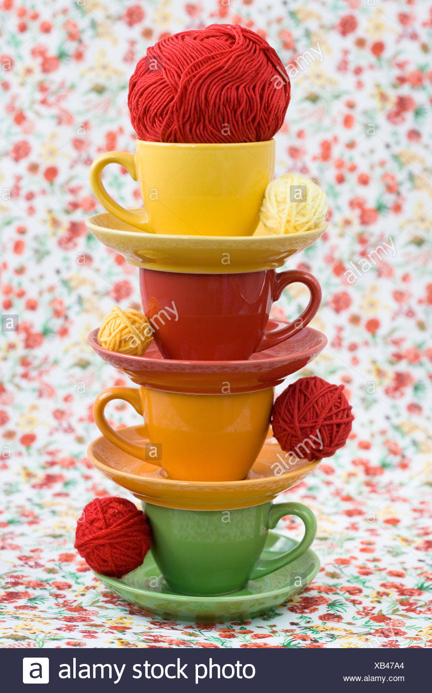 Four Colorful Cups And Balls Of Yarn On A Background Of A Red