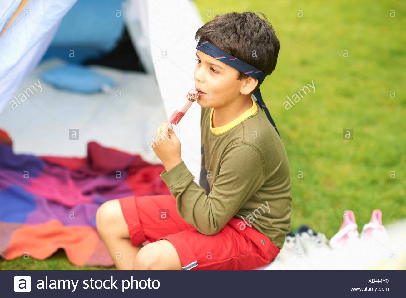 Download Boy eating ice lolly in front of homemade tent in garden ... Yellowimages Mockups