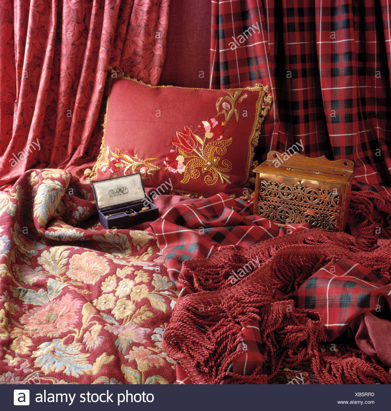 Close Up Of Red Cushion And Red Tartan And Floral Throws With