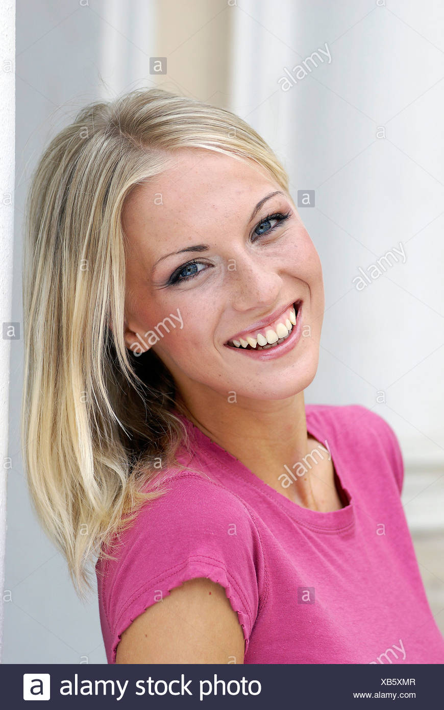 Female With Long Blonde Hair Wearing A Bright Pink Top And