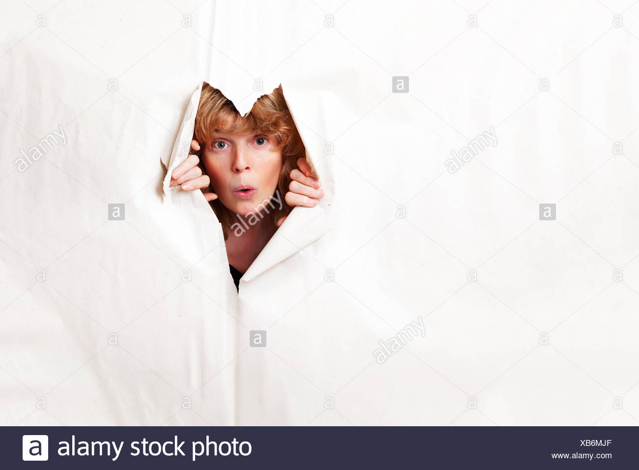 Woman looking through torn paper Stock Photo