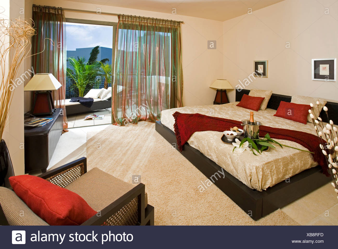 Modern Bedroom With Large Bed And Cream Carpet And View Of Balcony