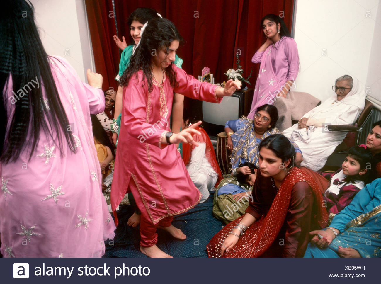 Asian Women Dancing In Living Room At Wedding Reception At Home Uk
