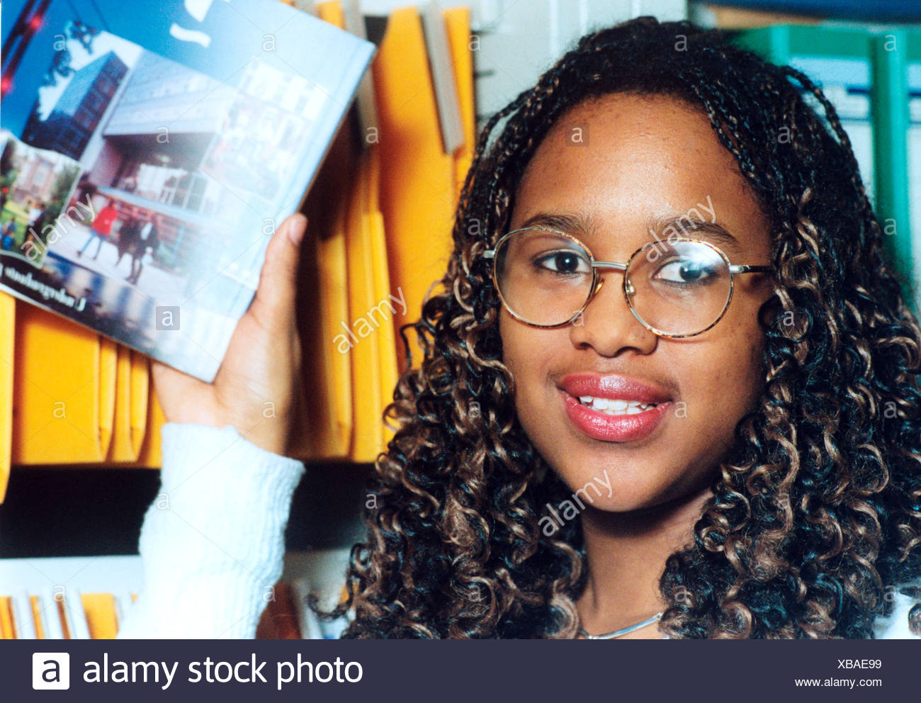Young female student at further education college looking at higher education prospectuses