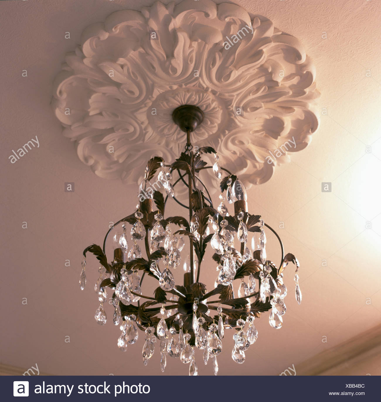 Close Up Of Glass Chandelier Hanging From Ornate Plaster Ceiling