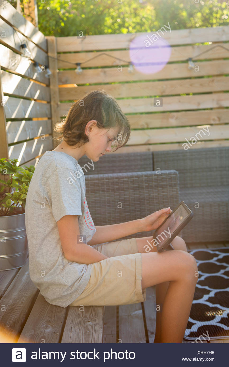 Sweden Boy 14 15 Using Tablet On Wooden Terrace Stock Photo