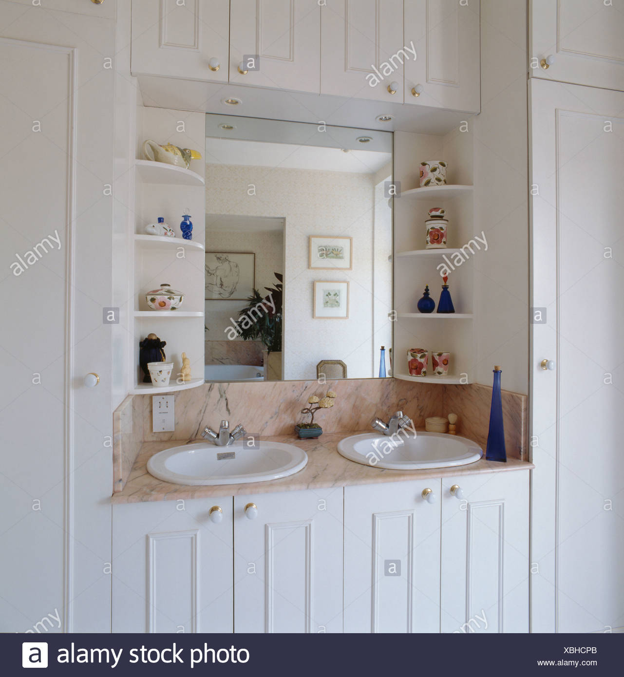Shelves On Either Side Of Mirror Above Double Basins In White Vanity Unit With Storage Cupboards In Traditional Bathroom Stock Photo Alamy