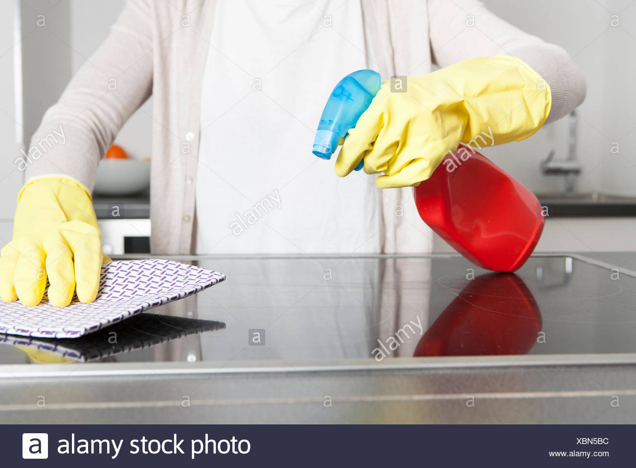 Woman Wearing Gloves Cleaning Ceramic Glass Cooktop With Spray