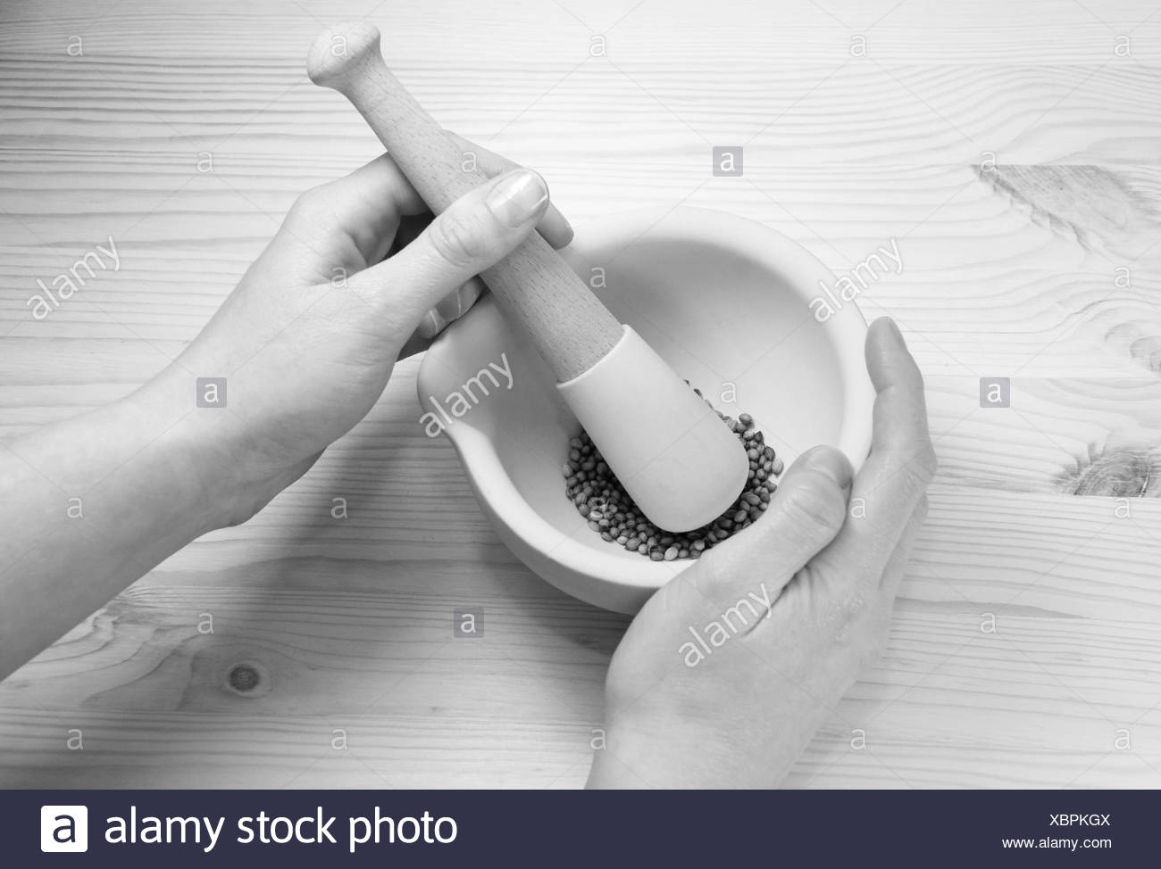 A Woman Uses A Pestle And Mortar On A Wooden Table To Crush Whole Coriander Seeds Monochrome Processing Stock Photo Alamy