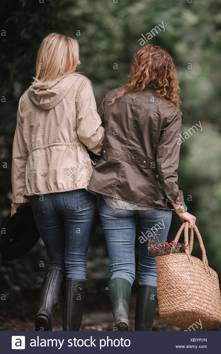 Two Women Arm In Arm Walking In Coats And Boots Along A Country Path With A Basket Stock Photo Alamy