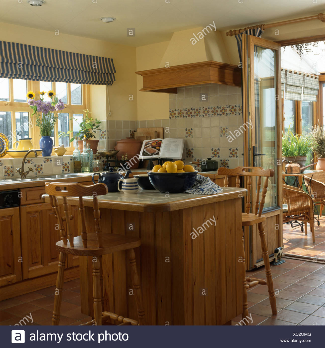 Pine stools at breakfast bar on island unit in a nineties kitchen with a  striped blind on the window Stock Photo - Alamy