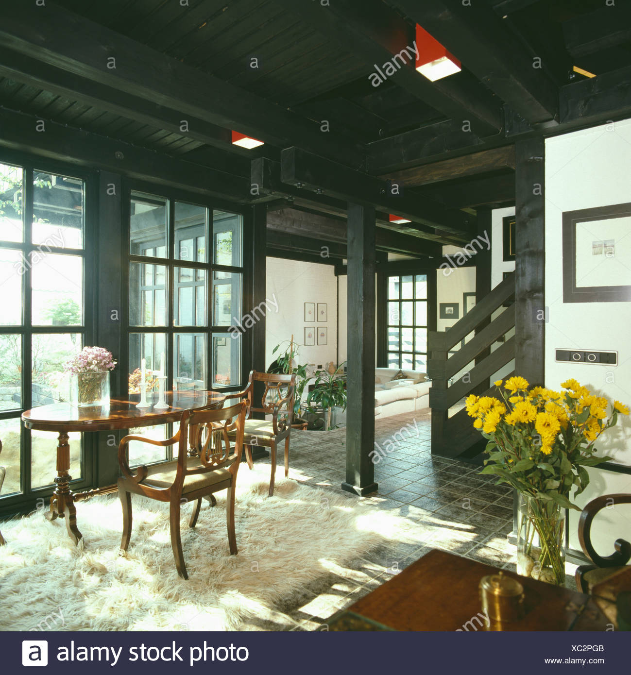 Antique Table And Chairs On Sheepskin Rug In Country Living Room With Painted Black Roof Stock Photo Alamy