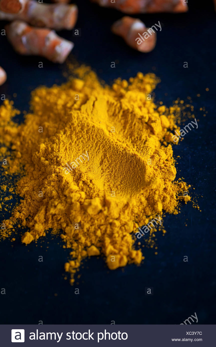 Ground yellow turmeric powder on the black surface Stock Photo