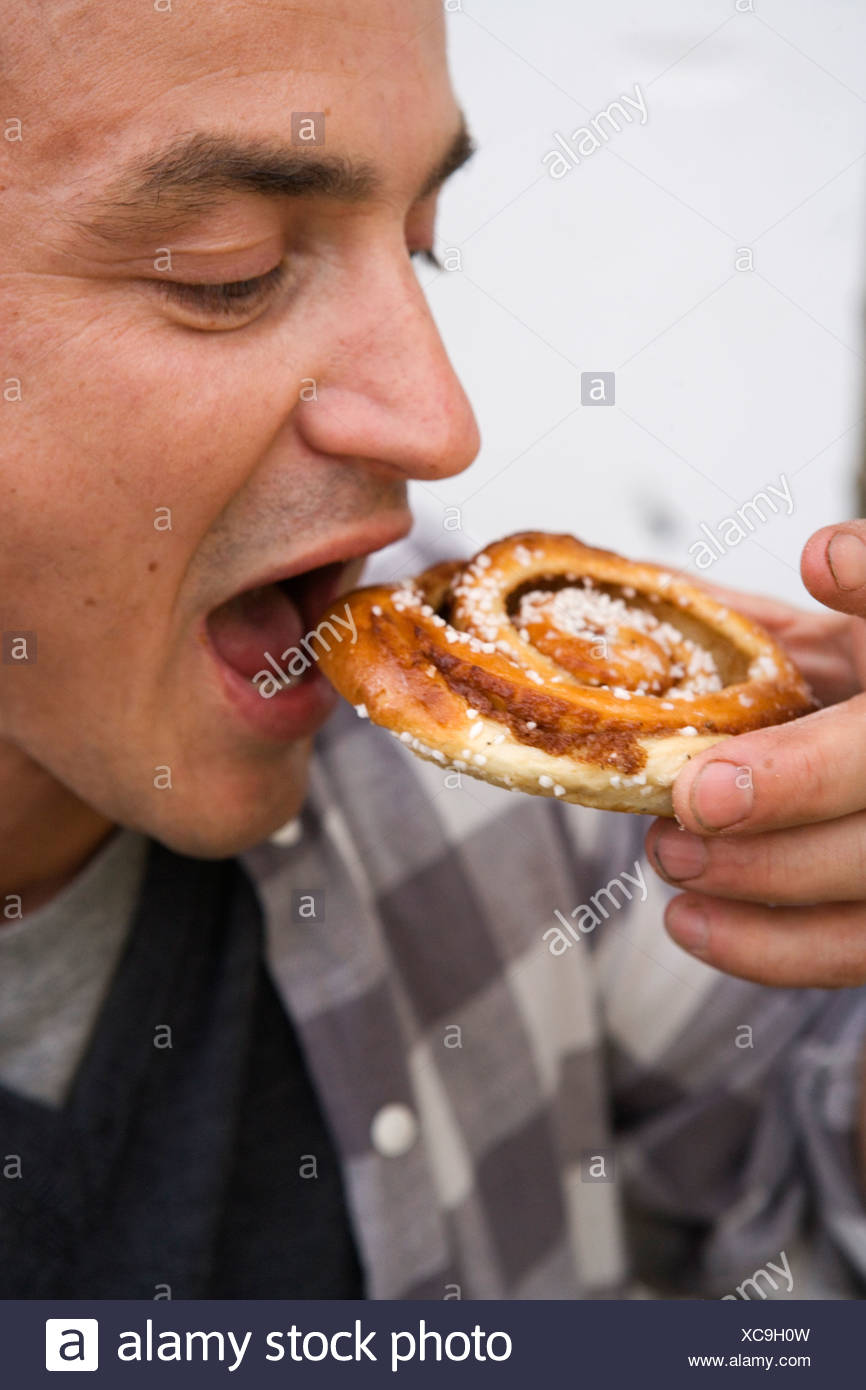 A man eating a cinnamon roll Stock Photo - Alamy