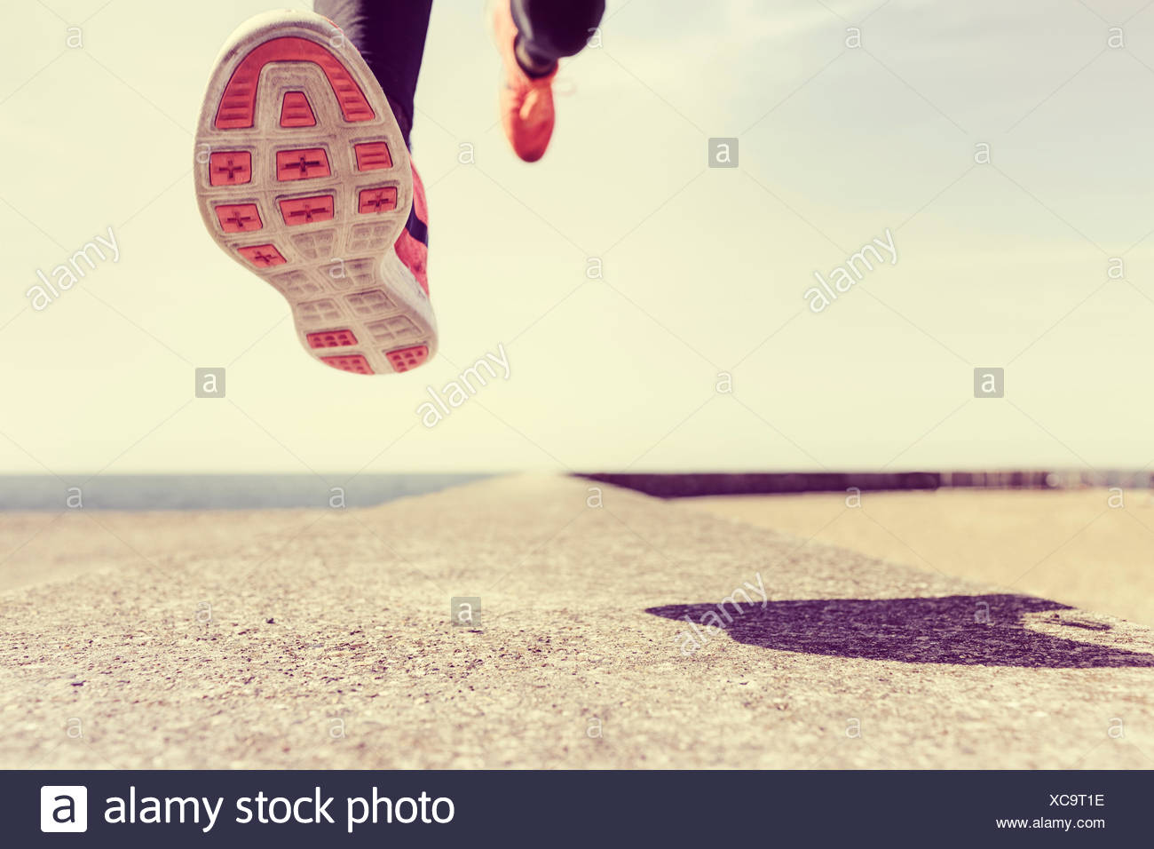 Young man running outdoors, mid air, low section Stock Photo