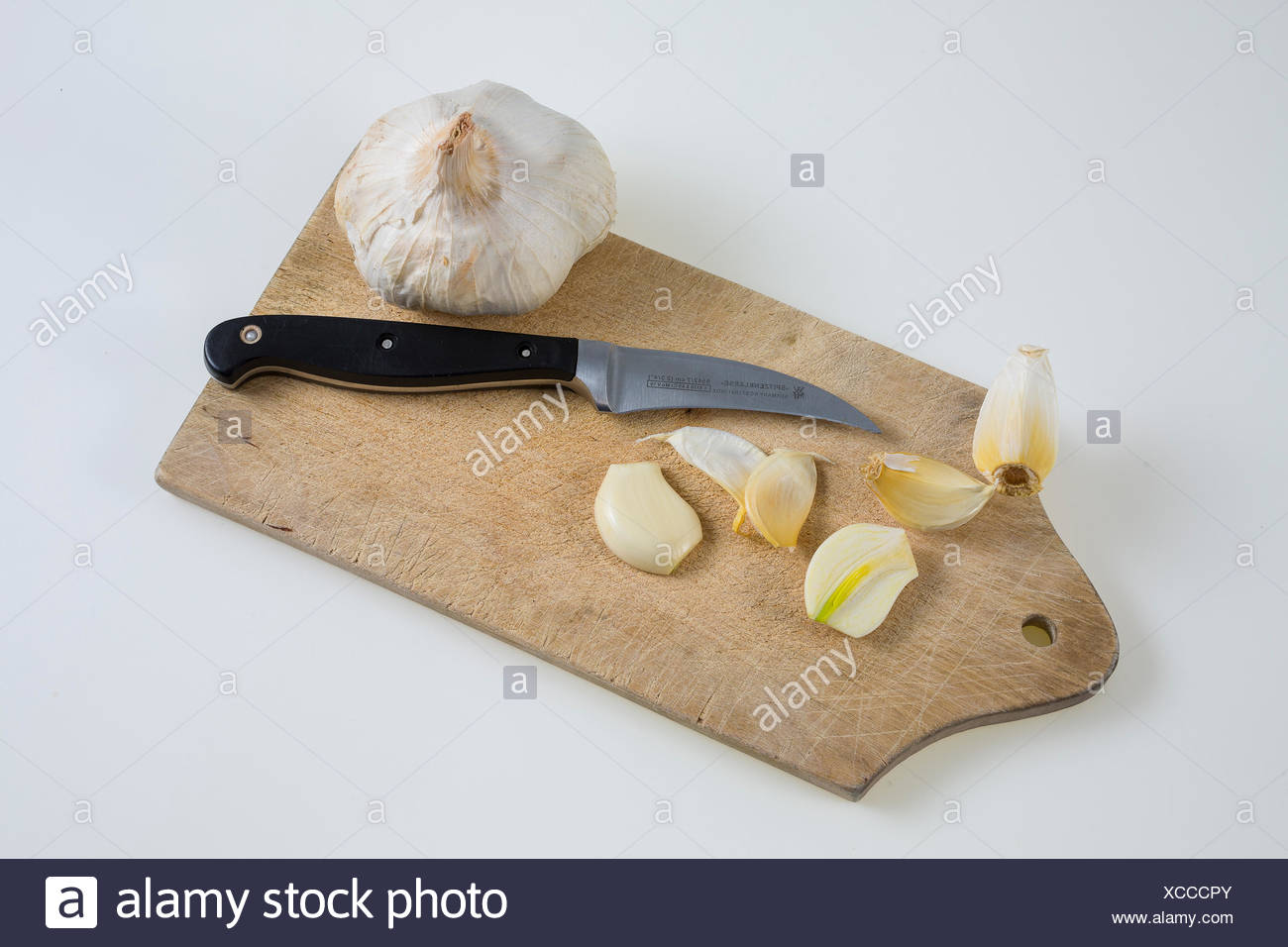 Knoblauch (Allium sativum) auf einem Küchenbrett mit Messer Stock Photo