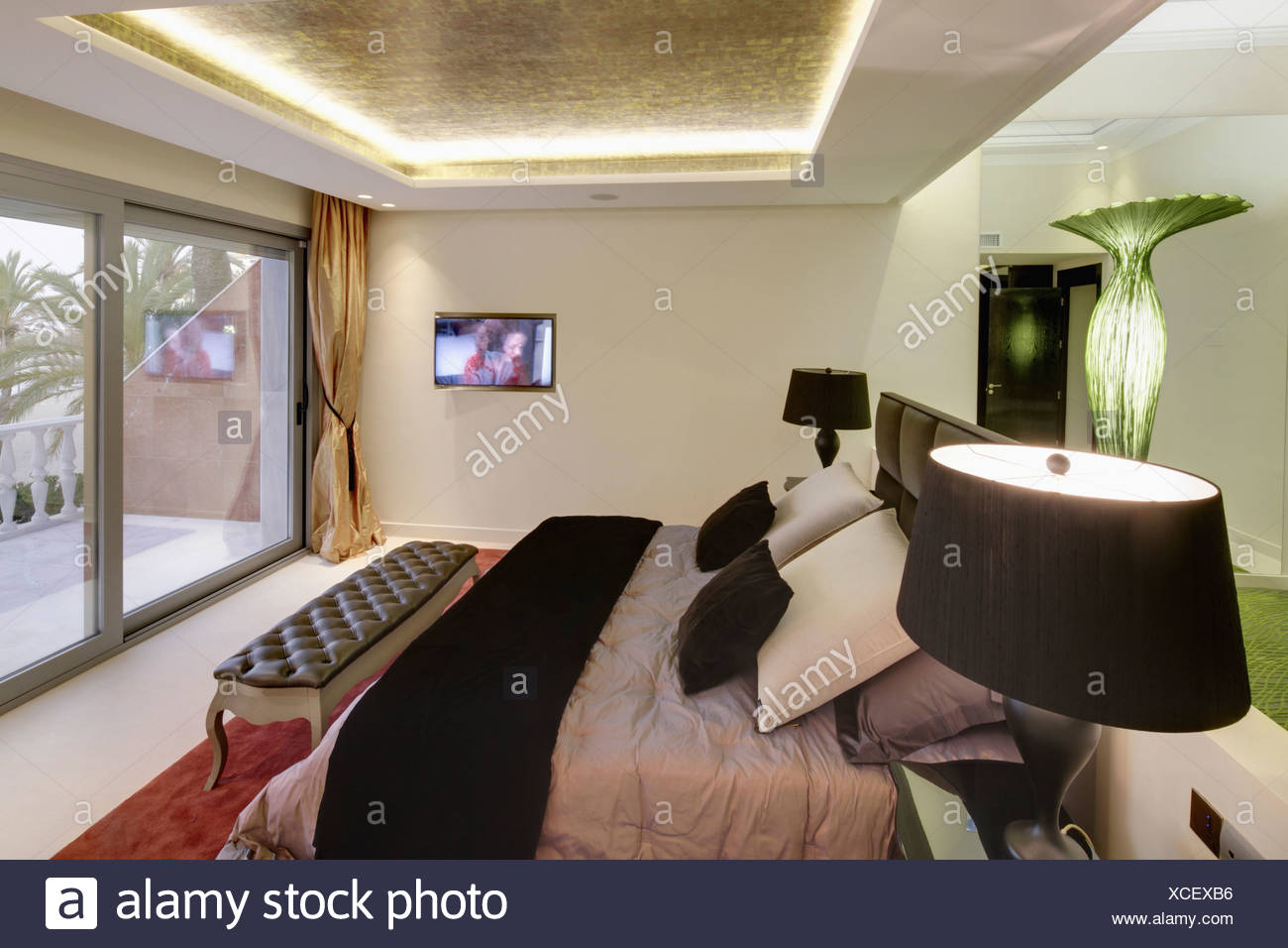 Black Lamp Beside Bed With Gray Quilt And Black Throw In