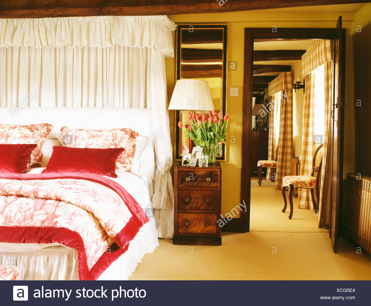 White Drapes Above Bed With Toile De Jouy Bedlinen And Red Silk