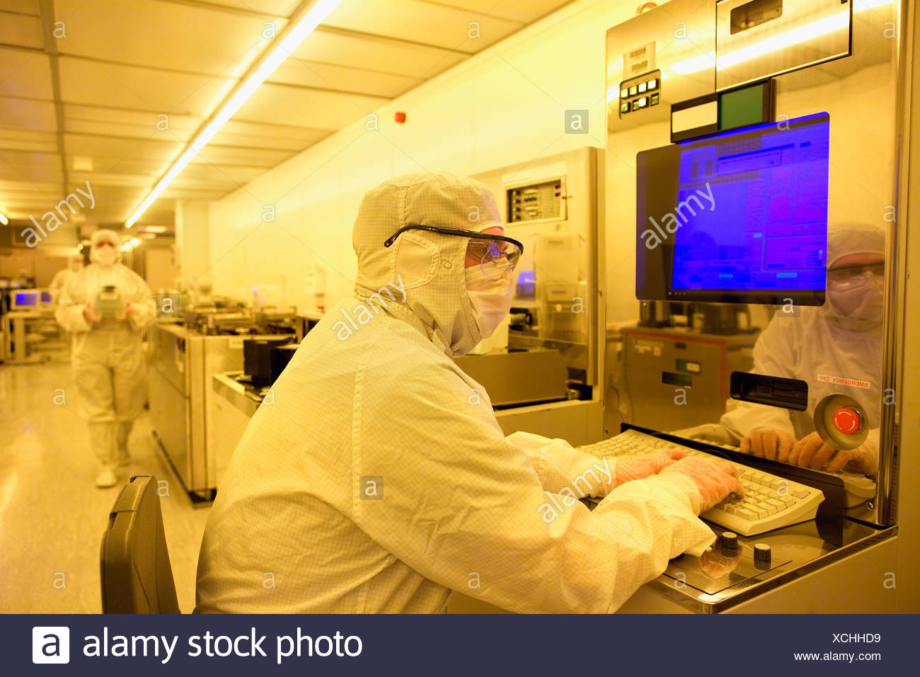 Scientist In Clean Suit Working At Computer In Silicon Wafer