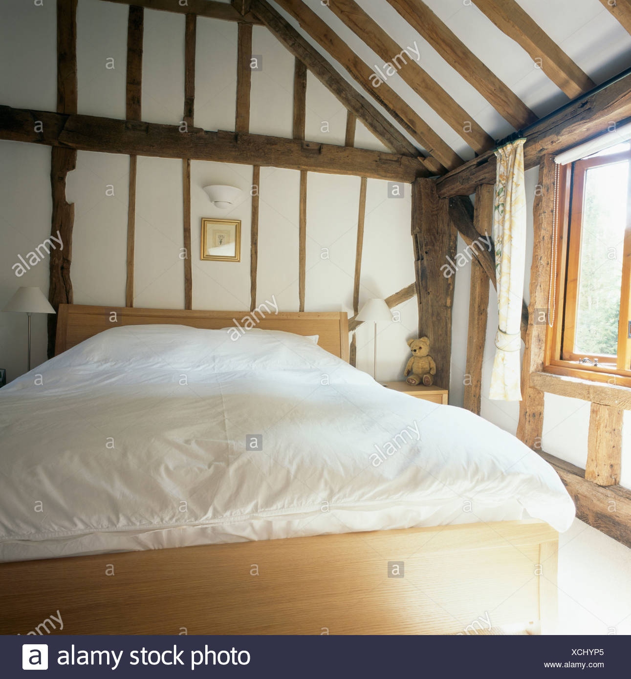 White Duvet On Simple Wooden Bed In Beamed Country Bedroom