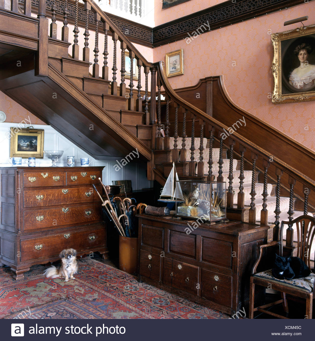 Antique Chests Of Drawers Below Staircase In A Large Deep Pink