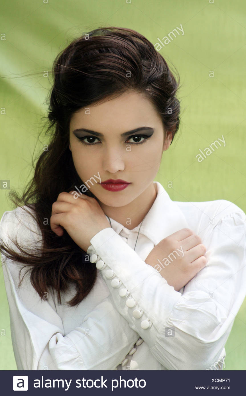 A Girl With Dark Hair And Make Up Wearing A White Top Looking At