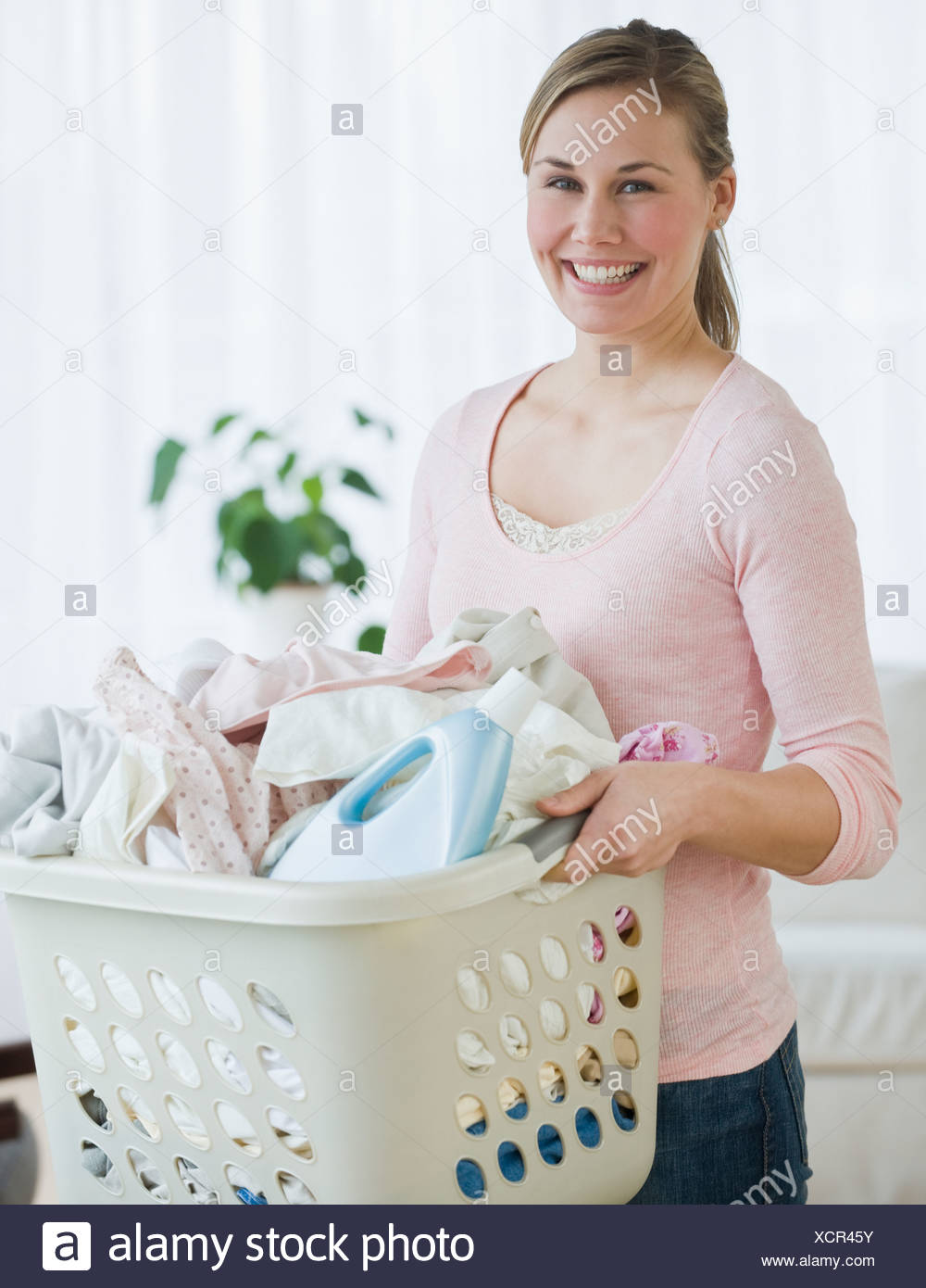 Woman holding laundry basket Stock Photo - Alamy